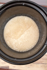 soap batter in a slow cooker with a thinner consistency and many small bubbles around the edges